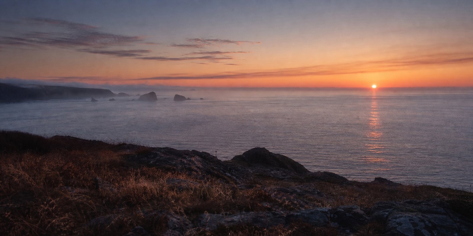 Last light over a rugged Pacific headland and calm ocean
